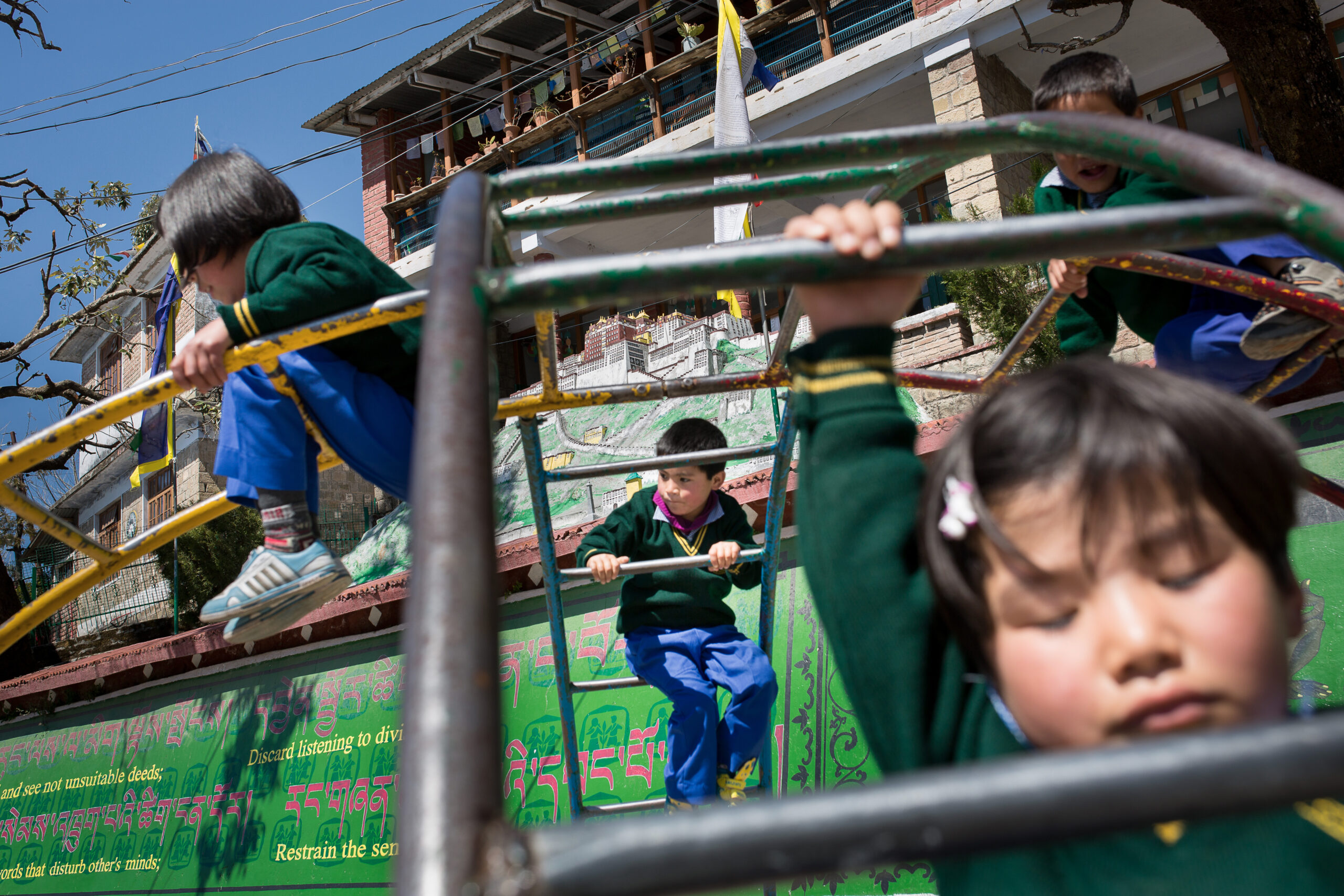 Des enfants s'amusent après leur pause déjeuner. A l'arrière-plan, la reproduction du palais du Potala, la résidence historique des dalai-lama à Lhassa, au Tibet. Sur la frise verte s'étalent, comme dans le reste de l'école, des devises de travail et de solidarité à l'intention des élèves. Le Tibetan Children's Village à Dharamsala, en Inde, accueille les enfants tibétains qui ont fui l'occupation chinoise.     //   Children having fun during their lunchtime. At the background, a copy of the Potala : the Dalai-lama's house in Tibet. On the green wall, as in the rest of the school, Tibetan principles such as "The others before myself".  The Tibetan Children's Village, in Dharamsala (India), welcomes tibetan children who ran away from the chinese occupation.