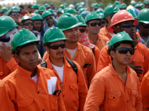 La photographie présente des ouvriers dans les Llanos colombiennes. Tous en tenue de travail orange portant un casque vert.